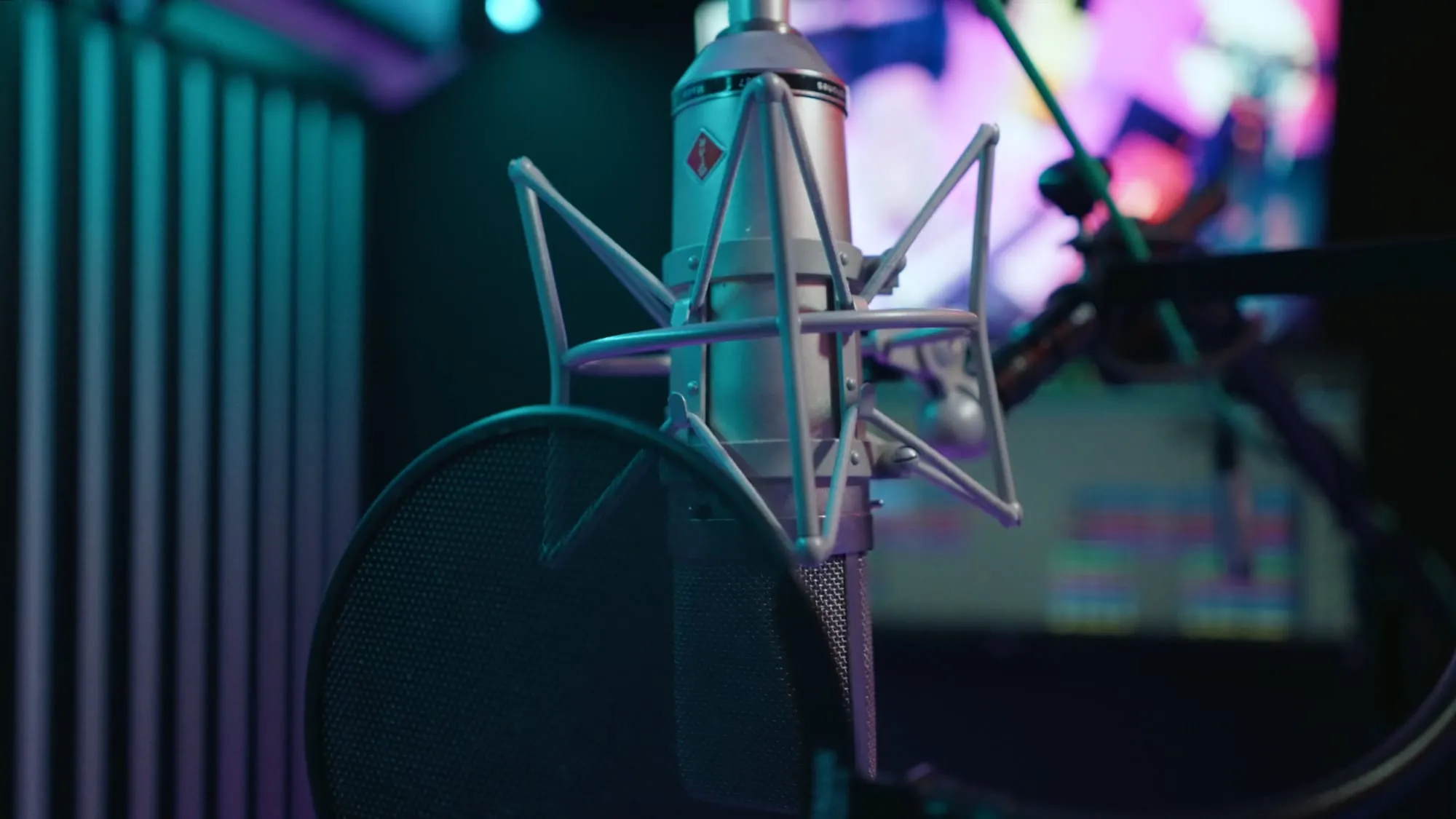 The condenser mic in the booth, pop filter on, session lit behind it.