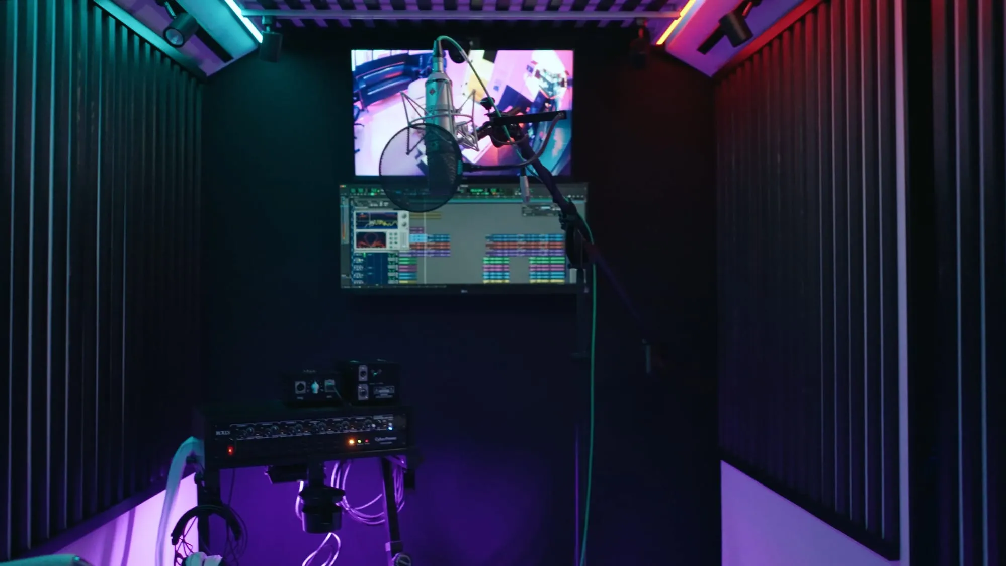 The vocal booth in purple and teal: mic up, session on the screen.