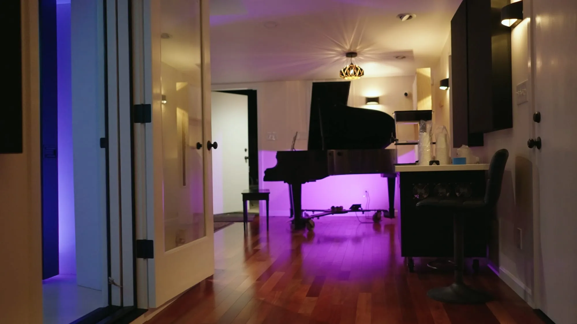 The hallway into the piano room, doors open, purple light on the keys.