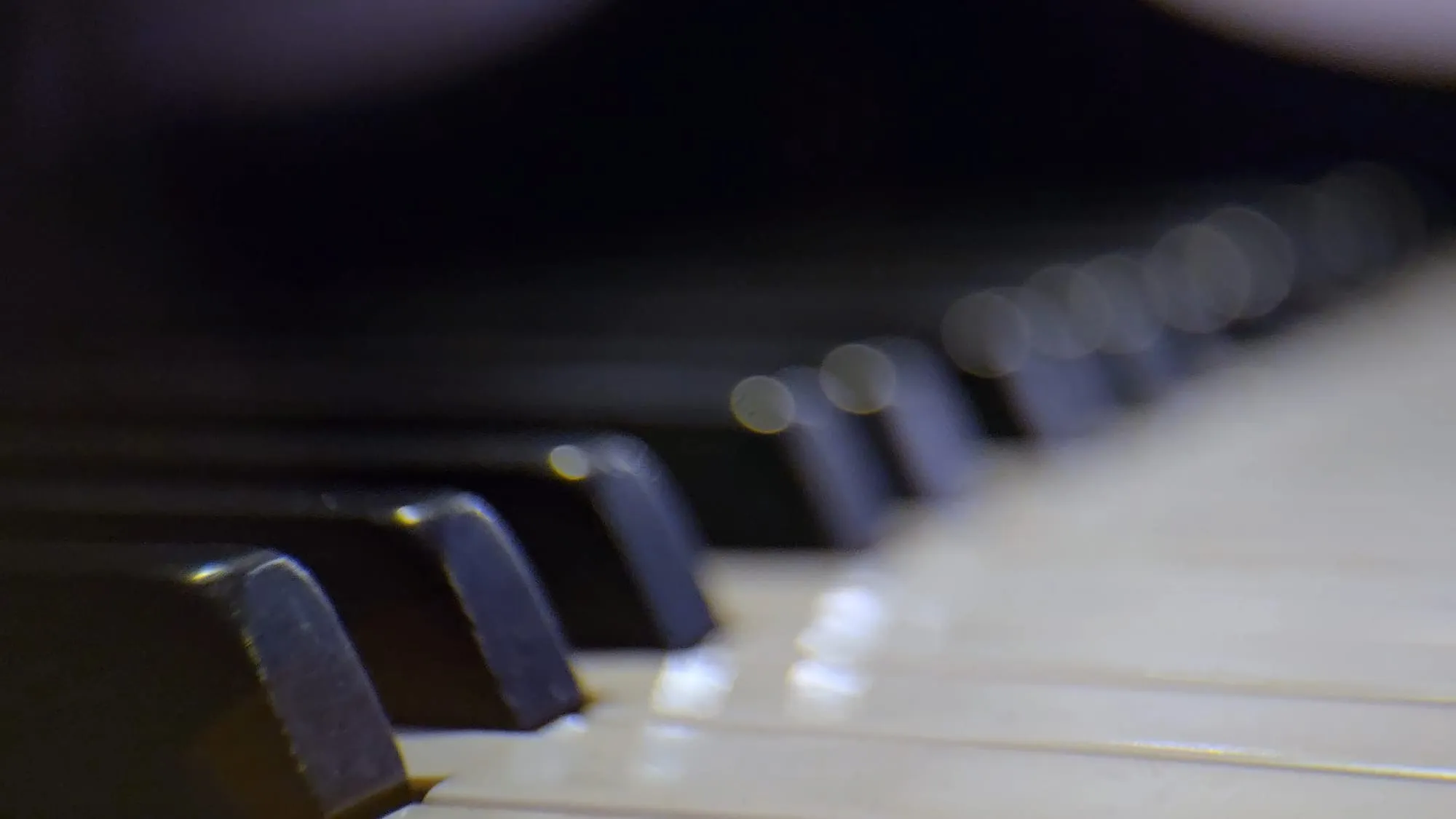 Piano keys up close in the live room, stage light catching the ivories.