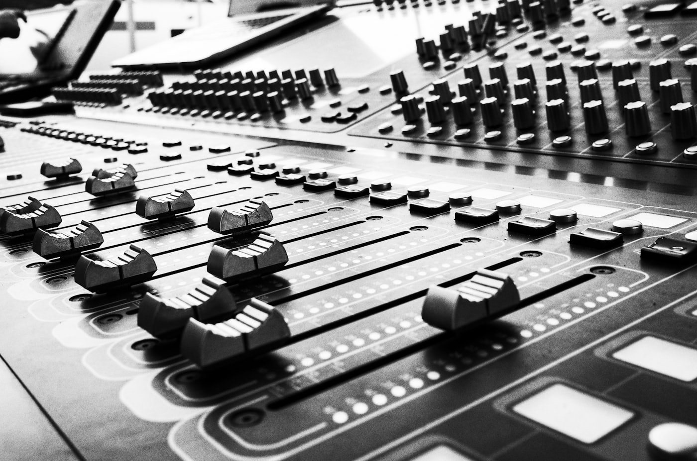 Close-up of mixing-console faders in black and white.