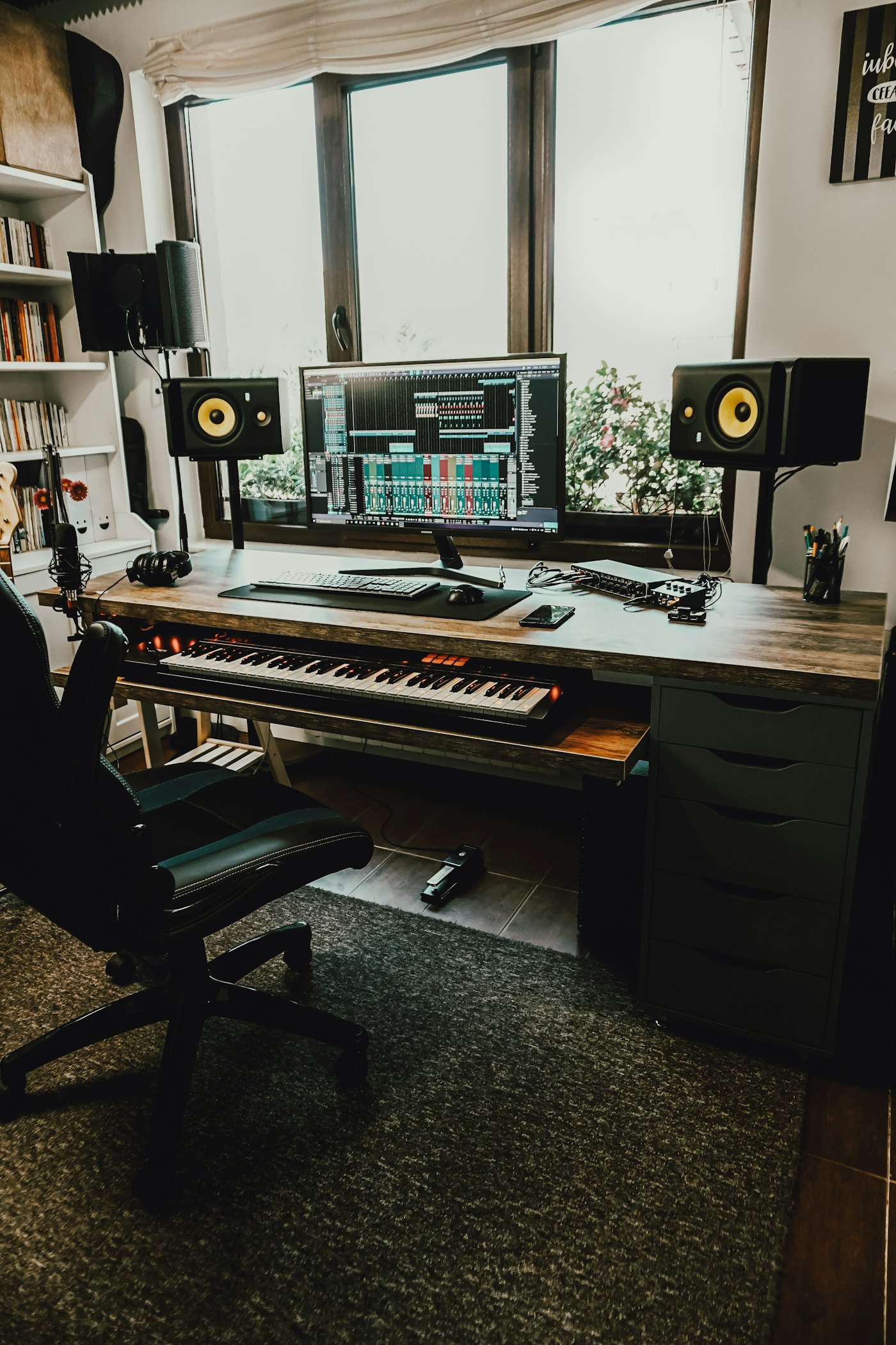 A weighted keyboard and studio monitors in a production room.