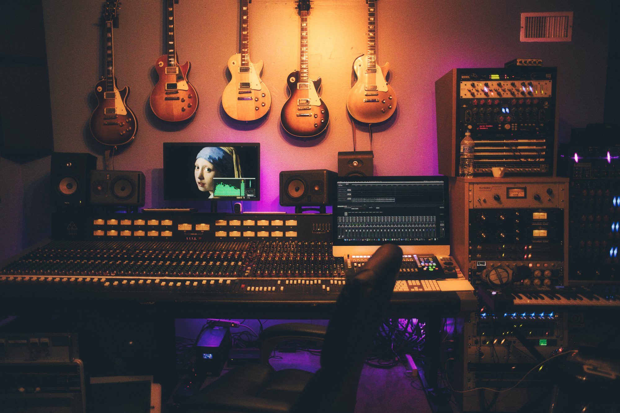 Electric guitars on the wall of a warmly lit control room.